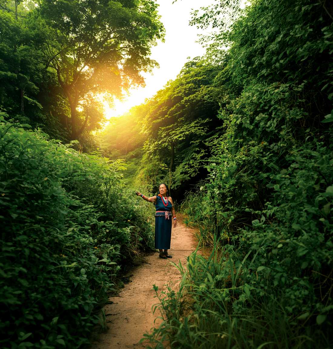 A woman walking a sunlit forest path in Puerto Cayo