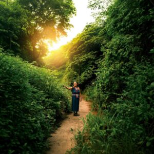 A woman walking a sunlit forest path in Puerto Cayo